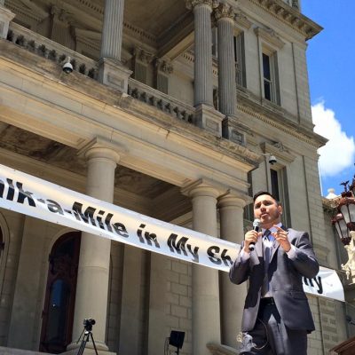 A man standing in front of a building with a banner.