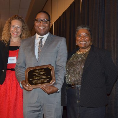 A group of people standing next to each other holding a plaque.