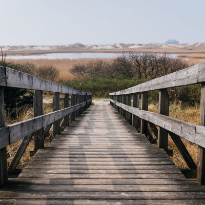 A wooden bridge leading to a sandy beach.