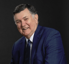 A man in a suit and tie smiles for the camera.