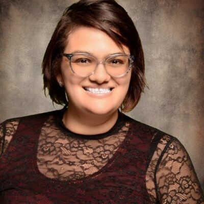 A woman wearing glasses and a lace top.