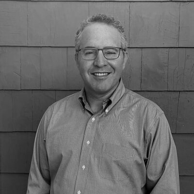 A black and white photo of a man smiling.