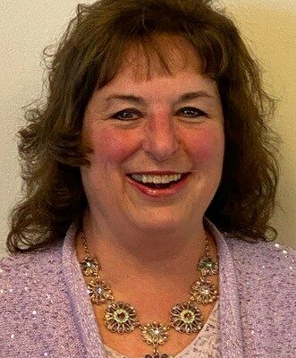 A woman wearing a purple cardigan and necklace.