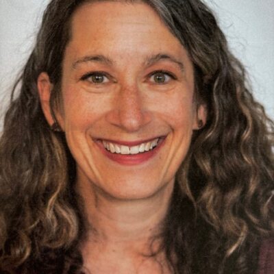 A woman with curly hair smiling for the camera.